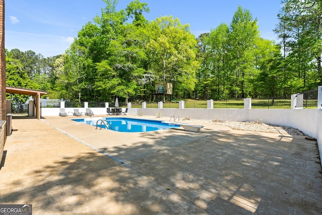 view of swimming pool featuring a diving board, fence, a patio, and a fenced in pool