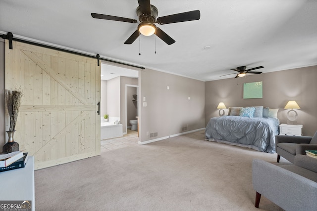 bedroom featuring a barn door, visible vents, ornamental molding, ensuite bath, and light colored carpet