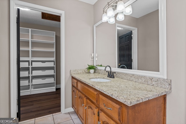 bathroom featuring tile patterned floors, vanity, a spacious closet, and a chandelier