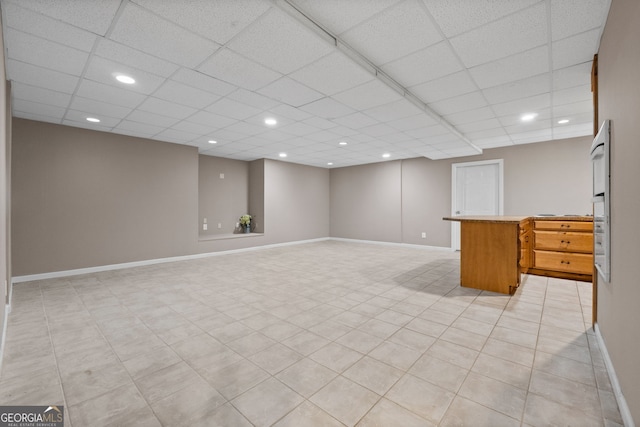 basement with recessed lighting, a paneled ceiling, and baseboards