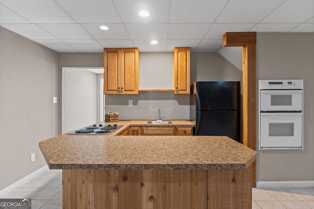 kitchen with double oven, light tile patterned floors, a sink, freestanding refrigerator, and stainless steel electric cooktop