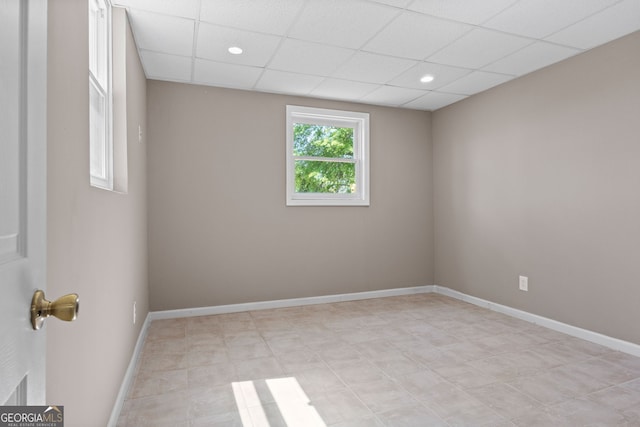empty room with recessed lighting, a drop ceiling, and baseboards