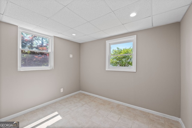 empty room featuring baseboards, a paneled ceiling, and recessed lighting