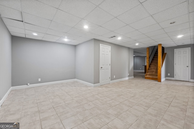 finished basement featuring recessed lighting, stairway, baseboards, and a paneled ceiling