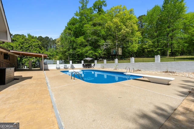 view of pool with fence, a patio area, a fenced in pool, and a diving board