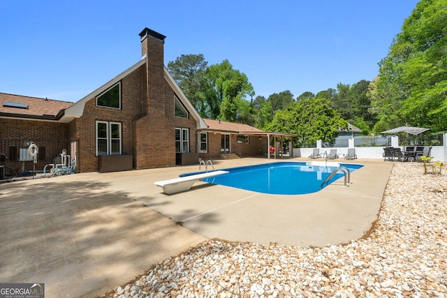 view of swimming pool featuring fence, a fenced in pool, a diving board, and a patio