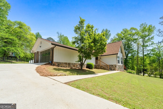 view of front of house featuring fence, a front lawn, concrete driveway, an attached garage, and stone siding
