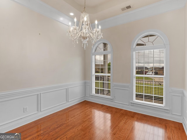 unfurnished dining area featuring a chandelier, wood finished floors, wainscoting, ornamental molding, and recessed lighting