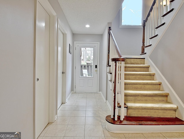 foyer entrance featuring recessed lighting, light tile patterned floors, baseboards, a textured ceiling, and stairs