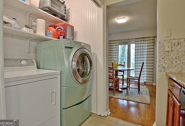 washroom featuring light wood-type flooring, a textured ceiling, laundry area, and independent washer and dryer