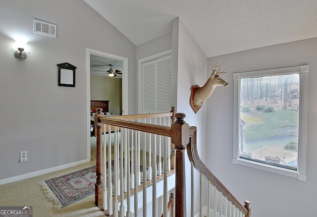 stairway with vaulted ceiling, baseboards, visible vents, carpet, and ceiling fan