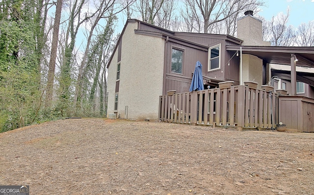 view of side of property with a chimney and stucco siding