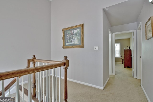 hall with baseboards, an upstairs landing, and light colored carpet