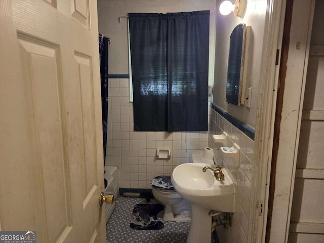 full bath featuring tile walls, wainscoting, tile patterned flooring, and toilet