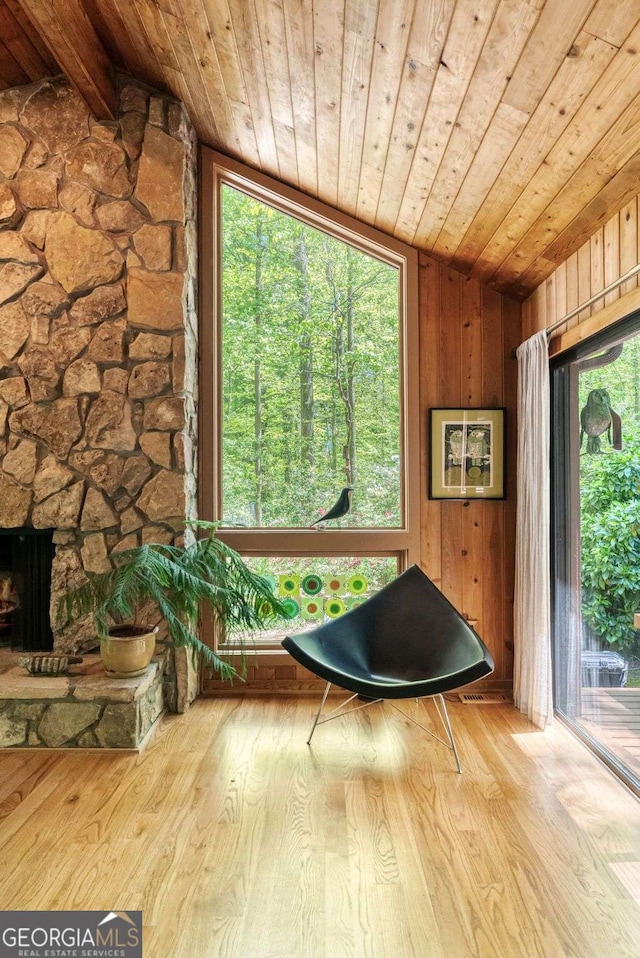 sitting room featuring wood ceiling, lofted ceiling, wooden walls, and a wealth of natural light
