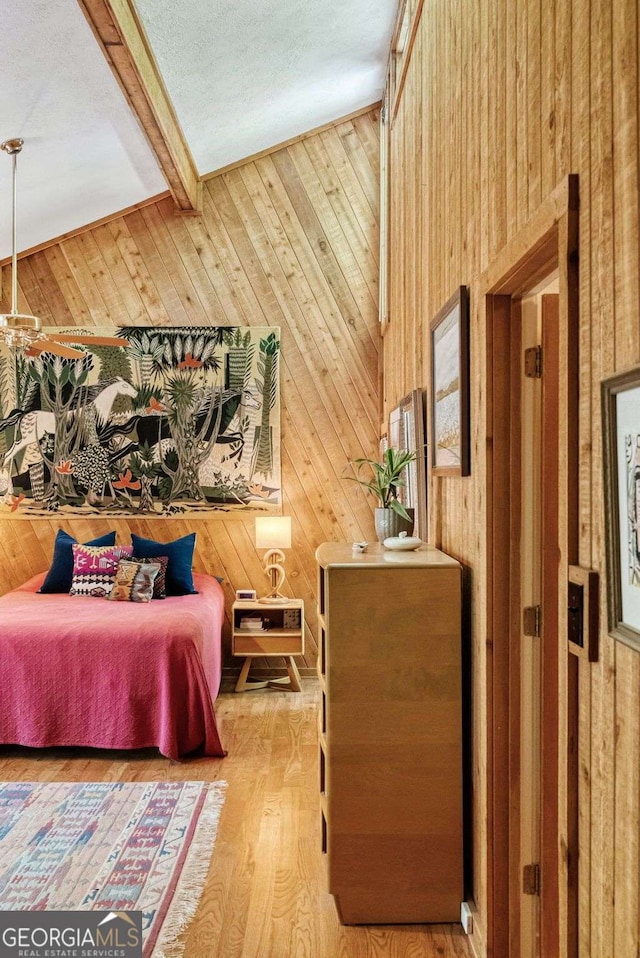 bedroom featuring wood finished floors, wood walls, and beam ceiling