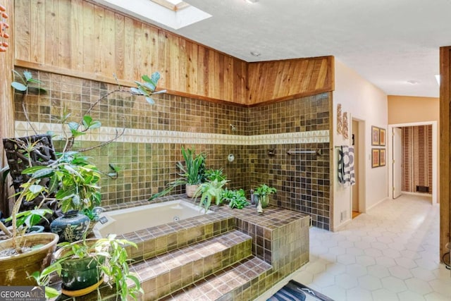 bathroom featuring a garden tub, tile patterned floors, and a skylight