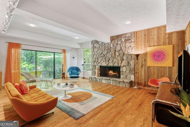living room featuring a fireplace, wood finished floors, beam ceiling, and wood walls
