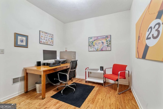 home office with wood finished floors, visible vents, and baseboards