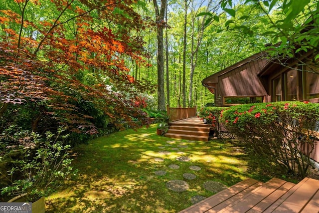 view of yard with a wooden deck and a wooded view