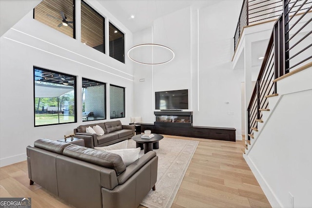 living area featuring recessed lighting, stairway, a high ceiling, wood finished floors, and baseboards