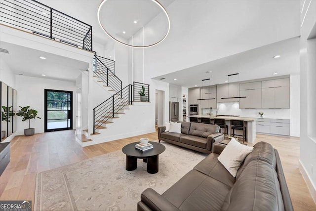 living area with baseboards, light wood-style flooring, stairs, and recessed lighting