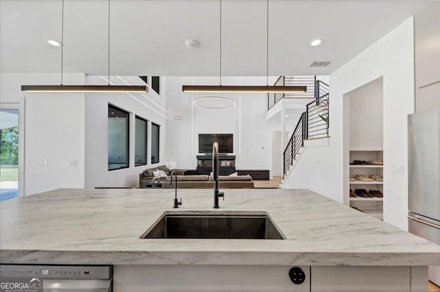 kitchen with a sink, open floor plan, visible vents, light stone counters, and appliances with stainless steel finishes