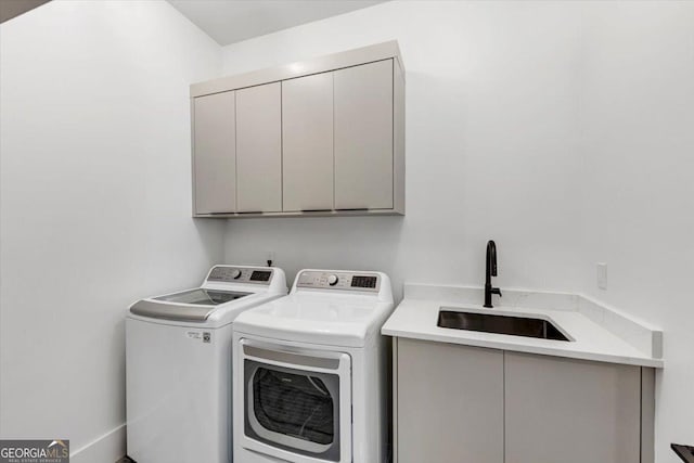 laundry room featuring washing machine and dryer, cabinet space, and a sink