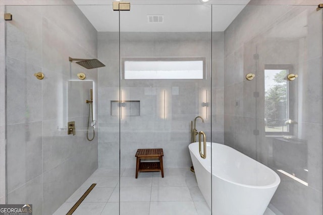 full bath with tile patterned flooring, visible vents, a walk in shower, tile walls, and a freestanding tub