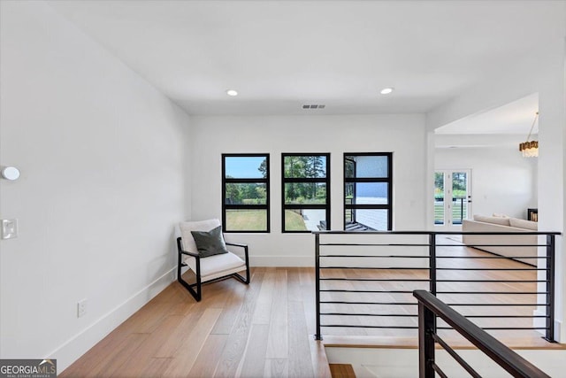 living area with visible vents, wood finished floors, recessed lighting, and an upstairs landing
