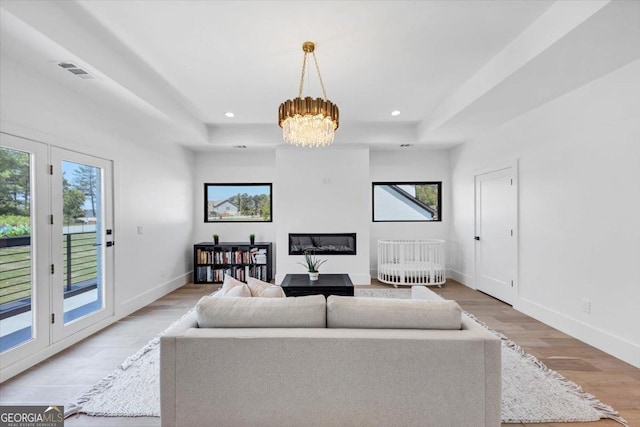 living area featuring a raised ceiling, visible vents, and light wood finished floors