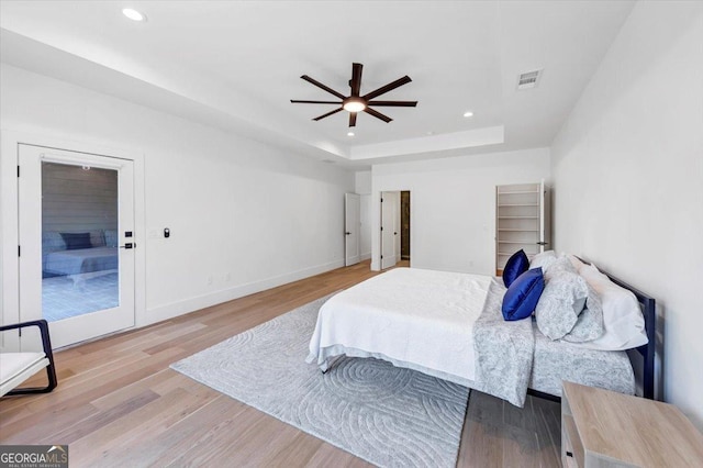 bedroom featuring wood finished floors, visible vents, recessed lighting, and a tray ceiling