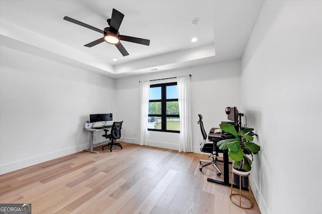 home office featuring a tray ceiling, light wood-style floors, baseboards, and recessed lighting