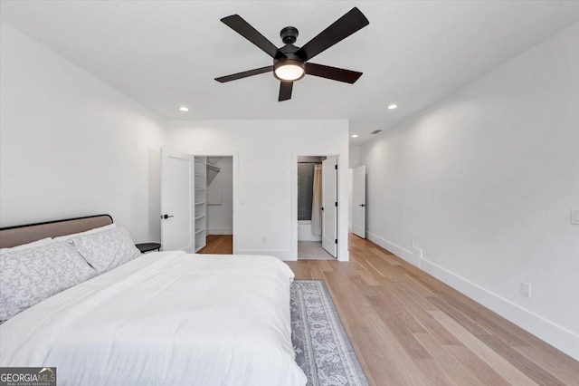 bedroom with light wood-type flooring, baseboards, a spacious closet, and recessed lighting