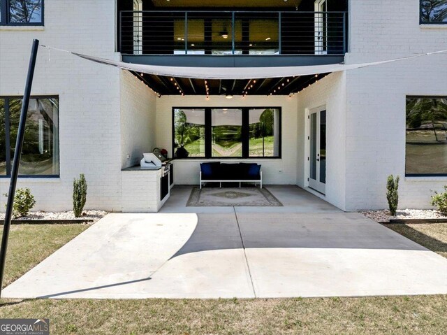 doorway to property featuring brick siding, a patio, a balcony, and french doors