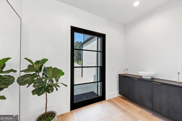 doorway featuring baseboards, recessed lighting, and light wood-style floors