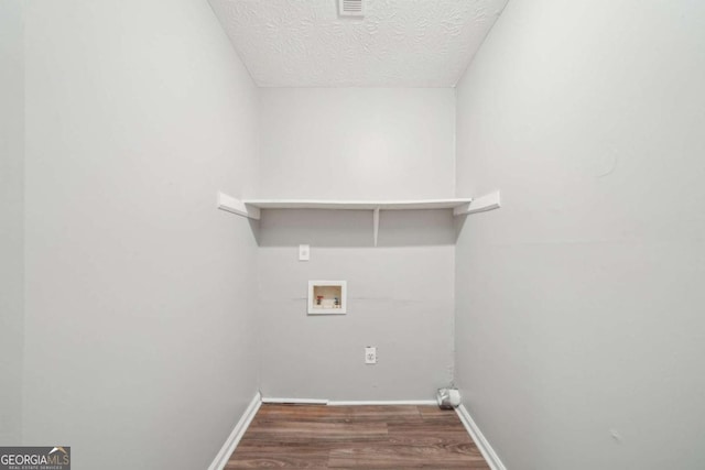 laundry area featuring a textured ceiling, baseboards, hookup for a washing machine, wood finished floors, and laundry area