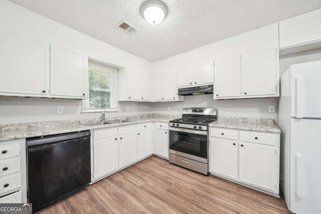 kitchen with under cabinet range hood, dishwasher, stainless steel range with gas stovetop, a sink, and freestanding refrigerator