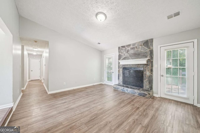 unfurnished living room with visible vents, a fireplace, wood finished floors, and a textured ceiling