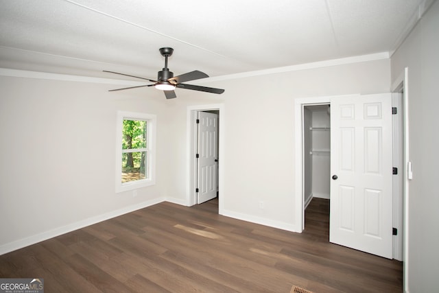 216 Howard Rd, Barnesville, GA 30204 - unfurnished bedroom featuring dark wood-style flooring, a spacious closet, baseboards, crown molding, and a ceiling fan