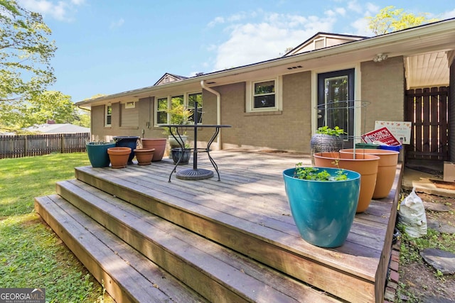 wooden terrace featuring fence and a yard