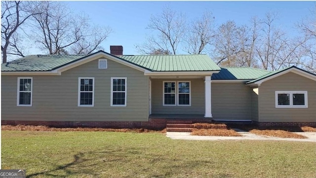 ranch-style house featuring a chimney, a front lawn, and metal roof