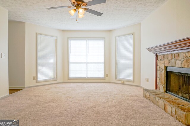 1166 Memory Ln, Lawrenceville, GA 30044 - unfurnished living room featuring carpet flooring, a ceiling fan, a stone fireplace, a textured ceiling, and baseboards