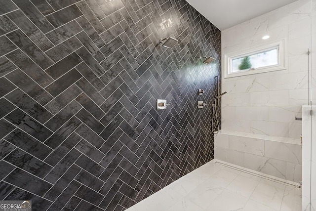 bathroom with marble finish floor and tiled shower