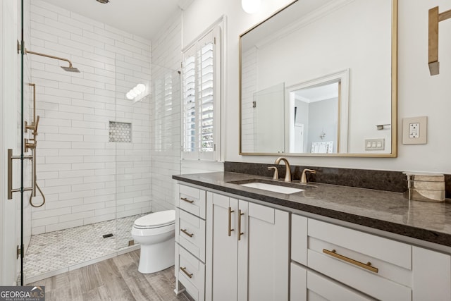 full bath featuring vanity, a tile shower, and toilet