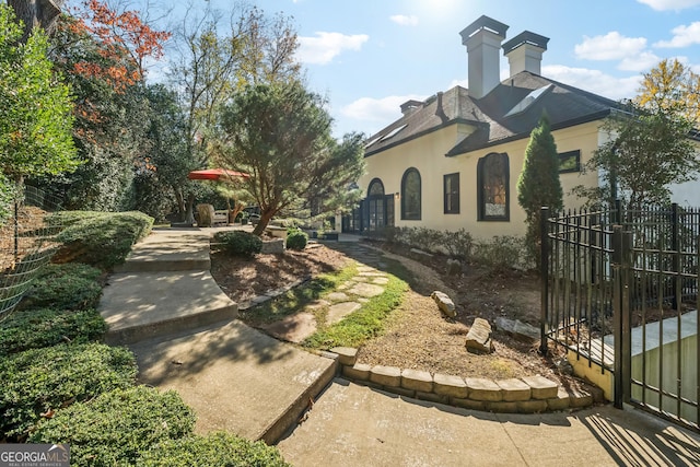view of home's exterior with a chimney, stucco siding, and fence