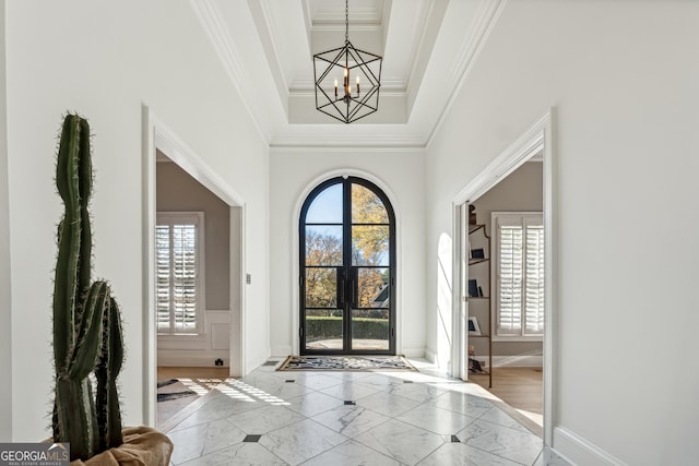 entryway featuring crown molding, a wealth of natural light, marble finish floor, and a notable chandelier