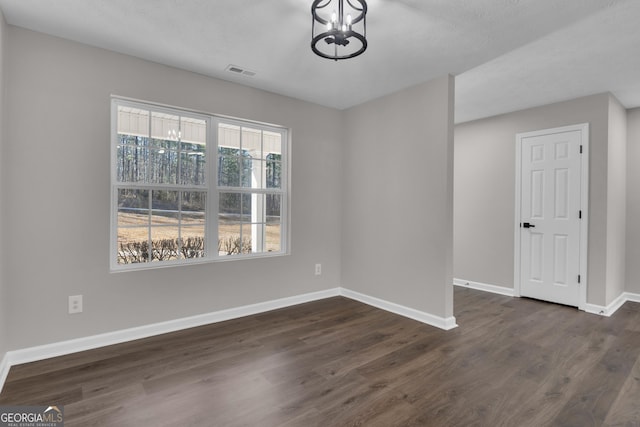 unfurnished dining area featuring baseboards, dark wood-type flooring, visible vents, and a notable chandelier