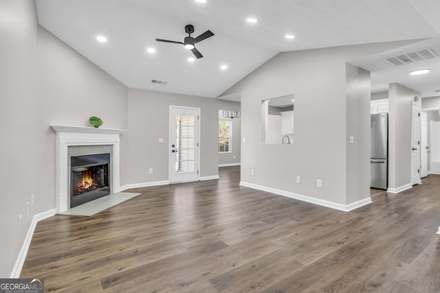 unfurnished living room featuring ceiling fan, vaulted ceiling, a tile fireplace, and visible vents