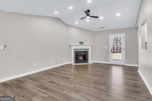 unfurnished living room with a fireplace with flush hearth, vaulted ceiling, visible vents, wood finished floors, and ceiling fan